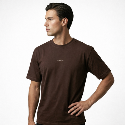 Man wearing a brown t-shirt with 'SAADI' logo on a white background